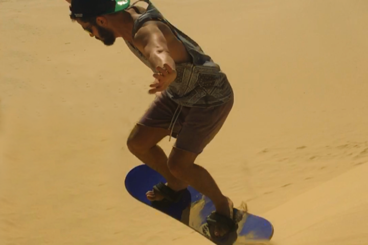 a person sand surfing down a sand dune in Port Stephens
