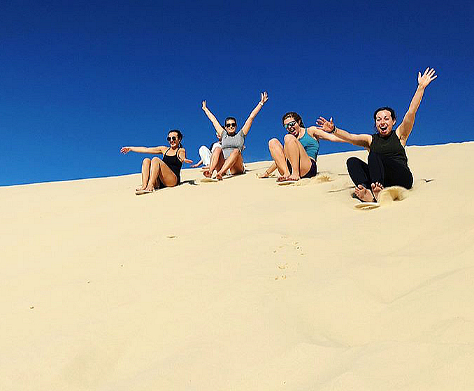 people sand boarding down a sand dune in Port Stephens