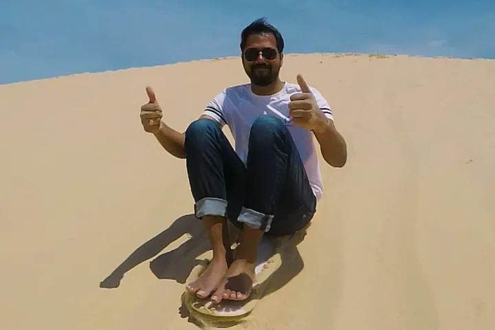 a man sand boarding down a sand dune in Port Stephens