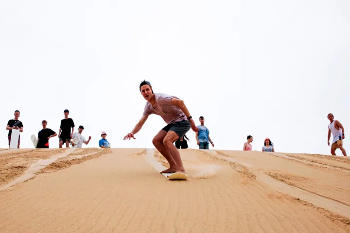 people sand surfing down a sand dune in Port Stephens
