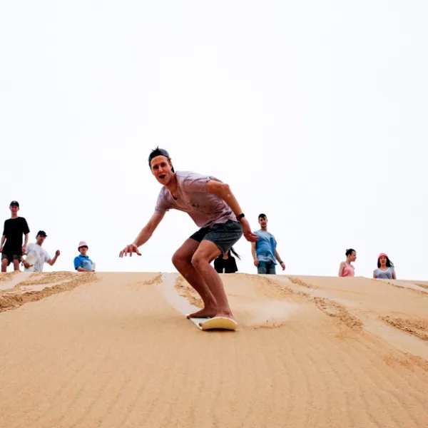 people sand surfing down a sand dune in Port Stephens