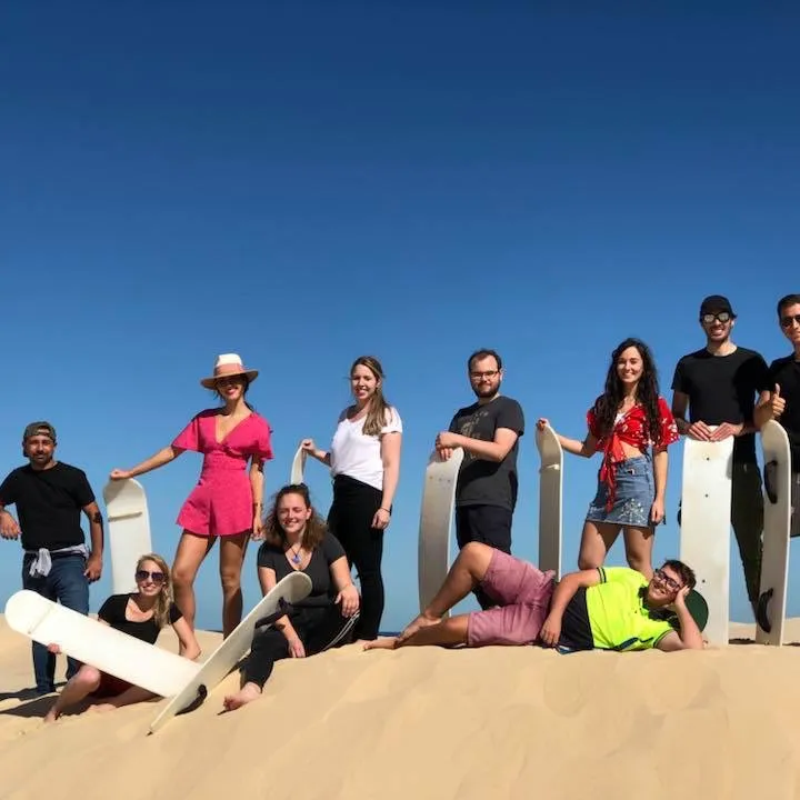 a group of people holding sand boards posing for the camera