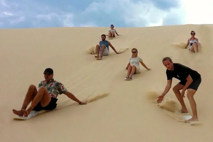 people sand boarding down a sand dune in Port Stephens