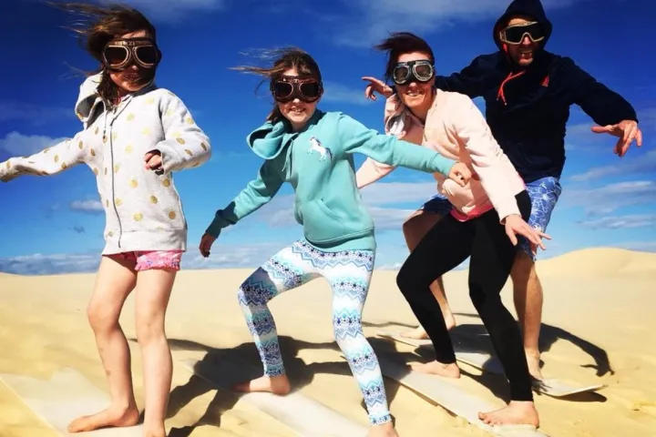a group of people sand surfing posing for the camera