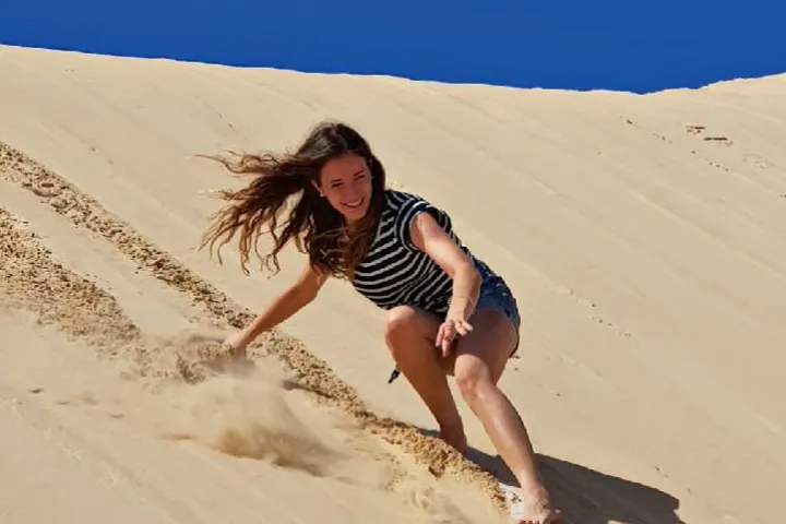a person sand surfing down a sand dune in Port Stephens